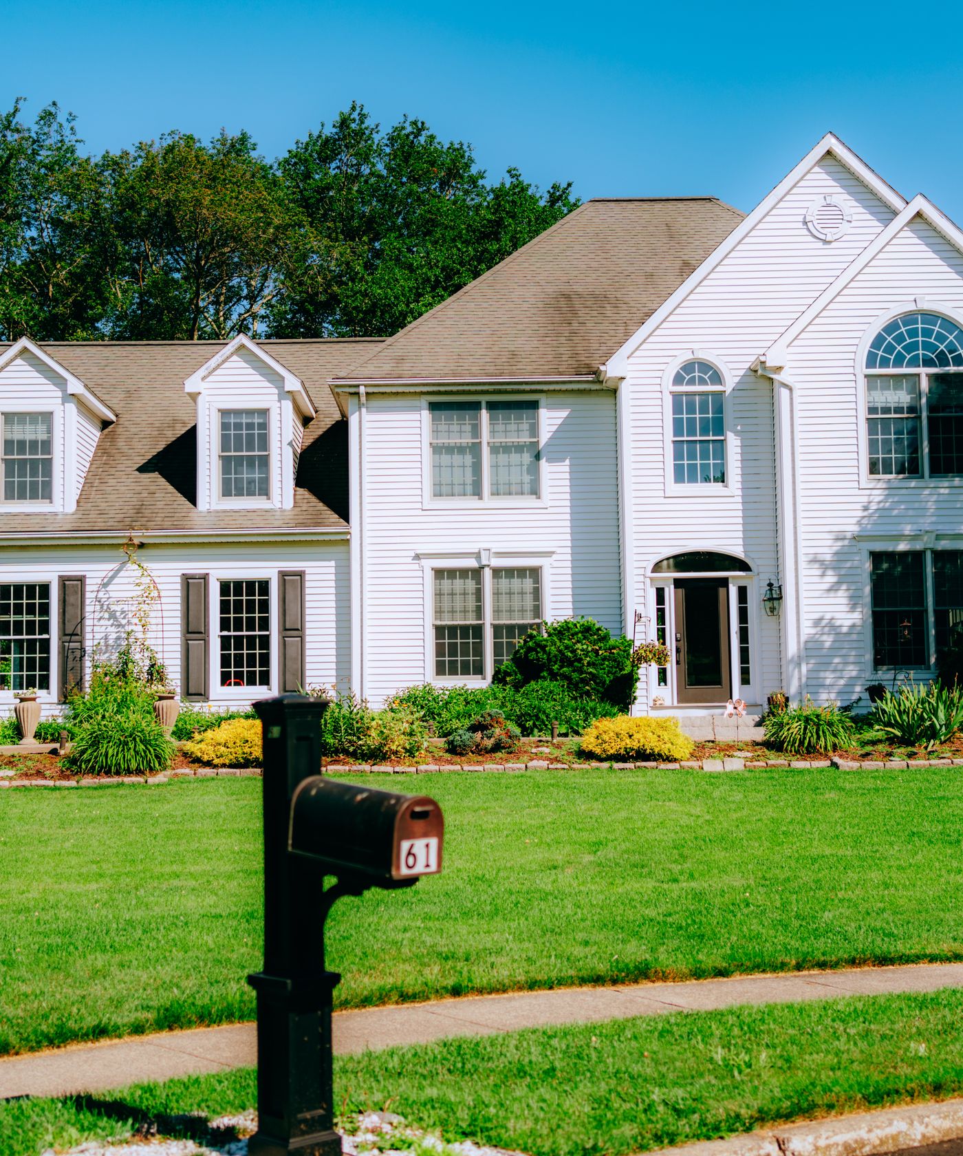 A white colonial home in Lake County with a freshly cut lawn and planted beds